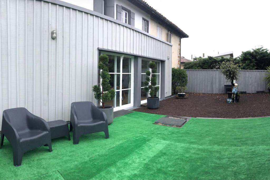 une cour avec deux chaises et une pelouse verte dans l'établissement Maison de caractère au village, à Pontenx-les-Forges