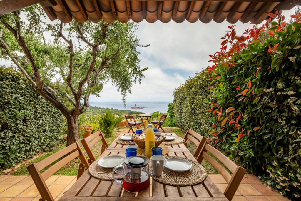 - une table en bois avec des chaises sur la terrasse dans l'établissement Résidence le Hameau de Cap Esterel - maeva Home - Maison 3 pièces 6 personnes - Prestige MAE-2101, à Saint-Raphaël