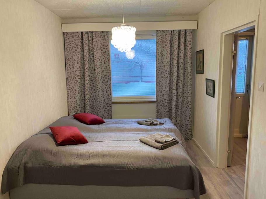 a bedroom with a bed with red pillows and a window at Huoneisto lähellä keskustaa in Pieksamaki