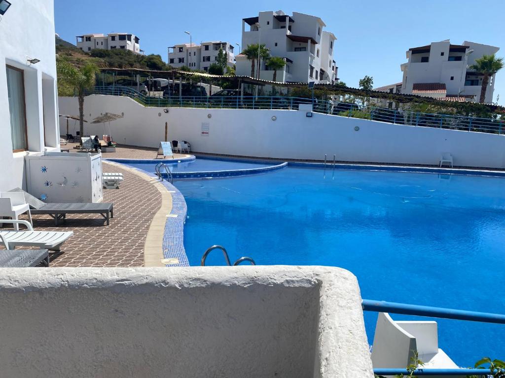 een groot blauw zwembad met gebouwen op de achtergrond bij Apparemment Noura in Tetouan