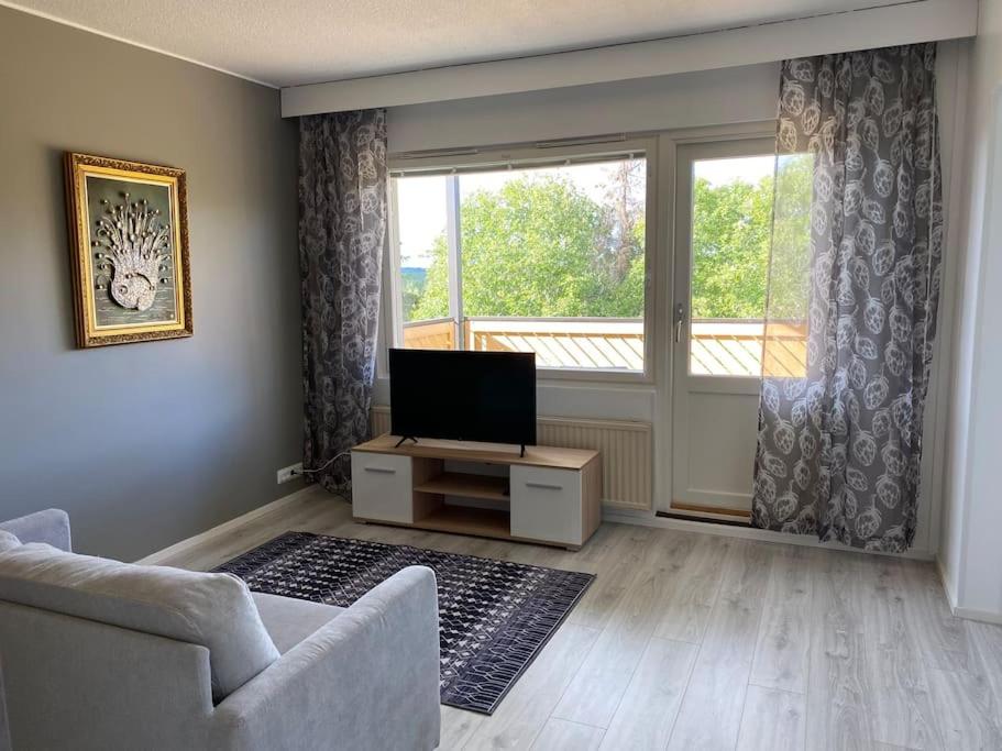 a living room with a tv and a large window at Viihtyisä huoneisto lähellä palveluita in Pieksamaki