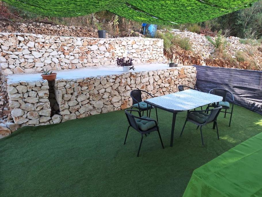 a table and chairs on a lawn with a stone wall at New, close to the beach apartment with terrace, grill, parking, 2-rooms in Trogir