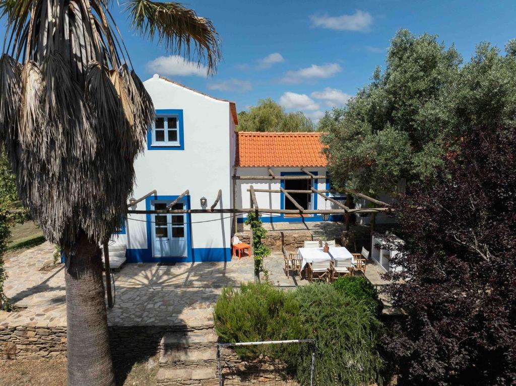 a white and blue house with a palm tree at Fonte Santa beautiful villa in Santiago do Cacém