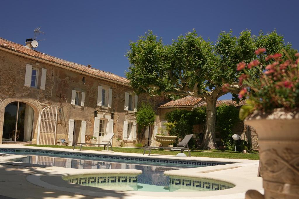 ein Haus mit einem Swimmingpool vor einem Gebäude in der Unterkunft LE MAS DES FLANERAIES in Althen-des-Paluds