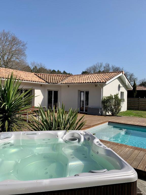 una vasca idromassaggio di fronte a una casa di Villa au calme en lisière de forêt a Lacanau