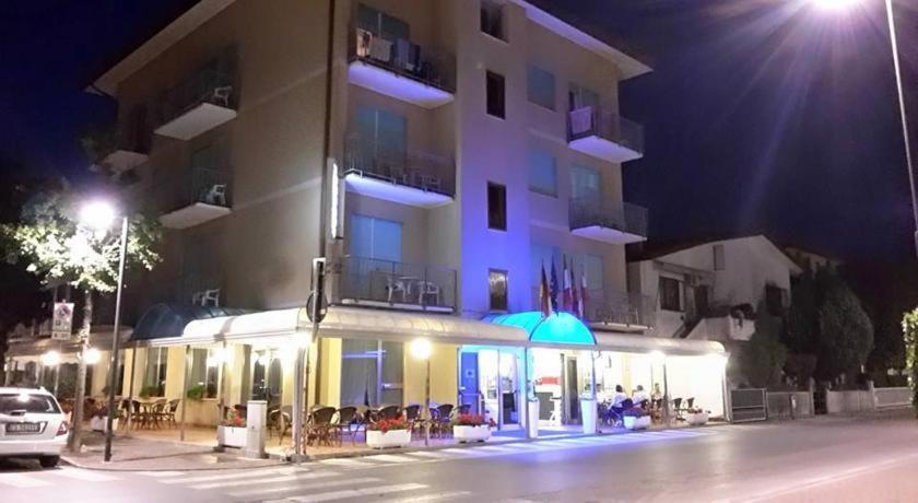 a building at night with tables and umbrellas in front of it at Hotel Fornaro in Caorle