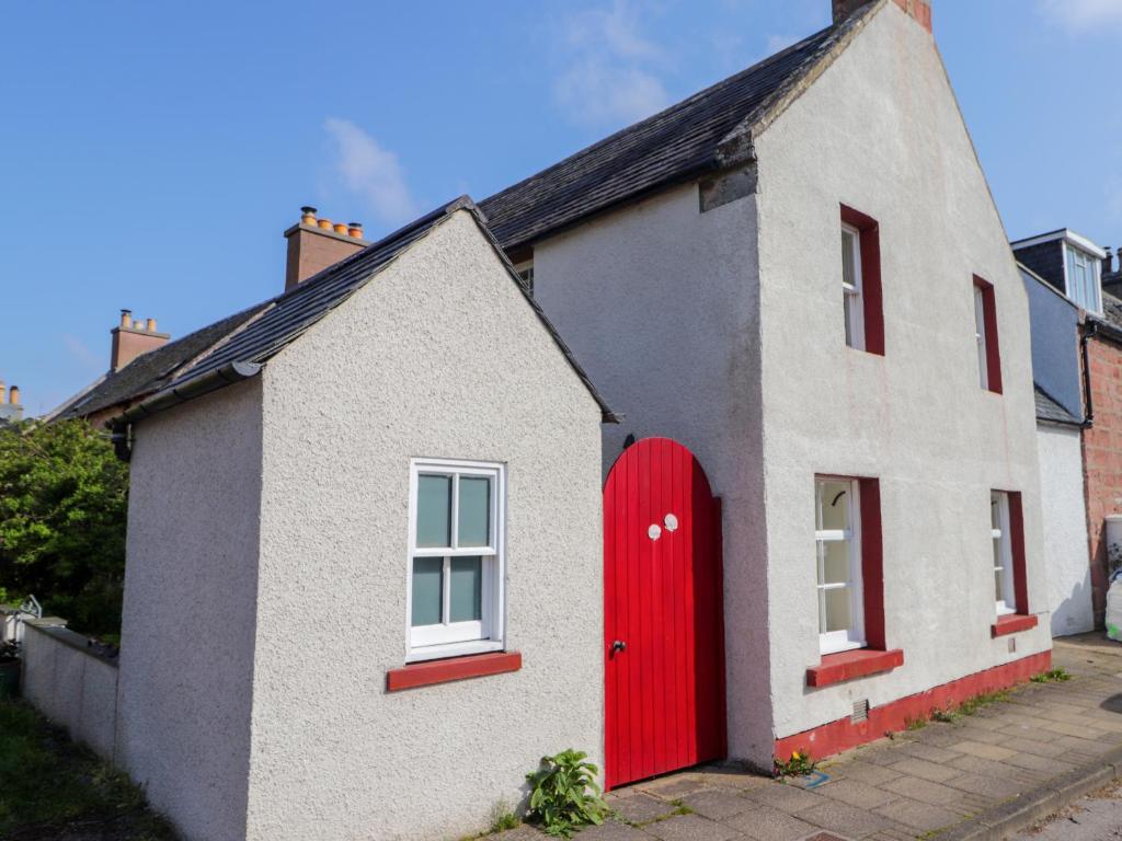a white and red house with a red door at Seashell Cottage in Cromarty
