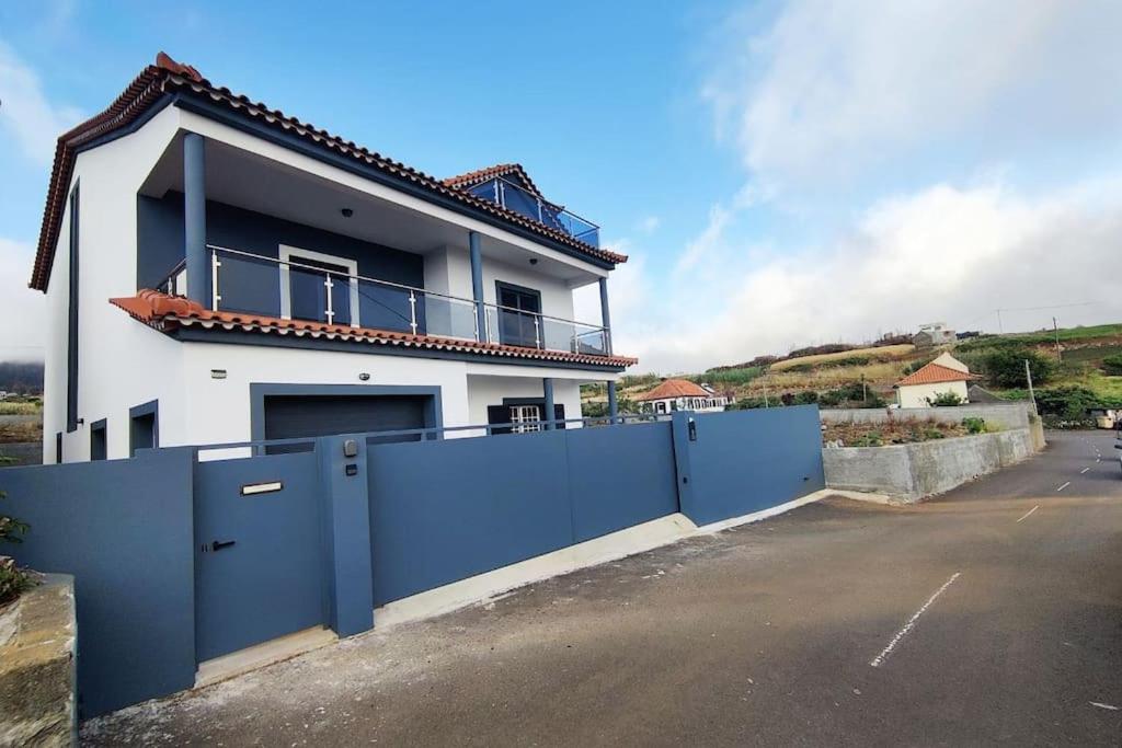 een wit huis met een blauw hek ervoor bij Casa Neto Jardim in Calheta