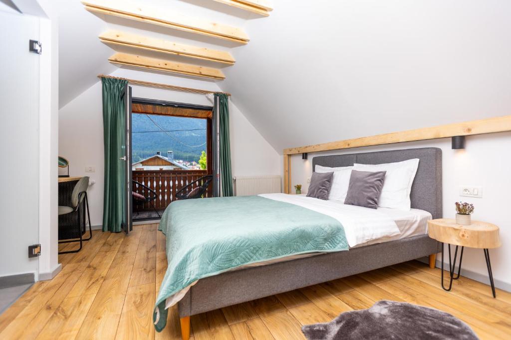 a bedroom with a large bed and a balcony at The Bear Chalet with Private Hot Tub in Buşteni