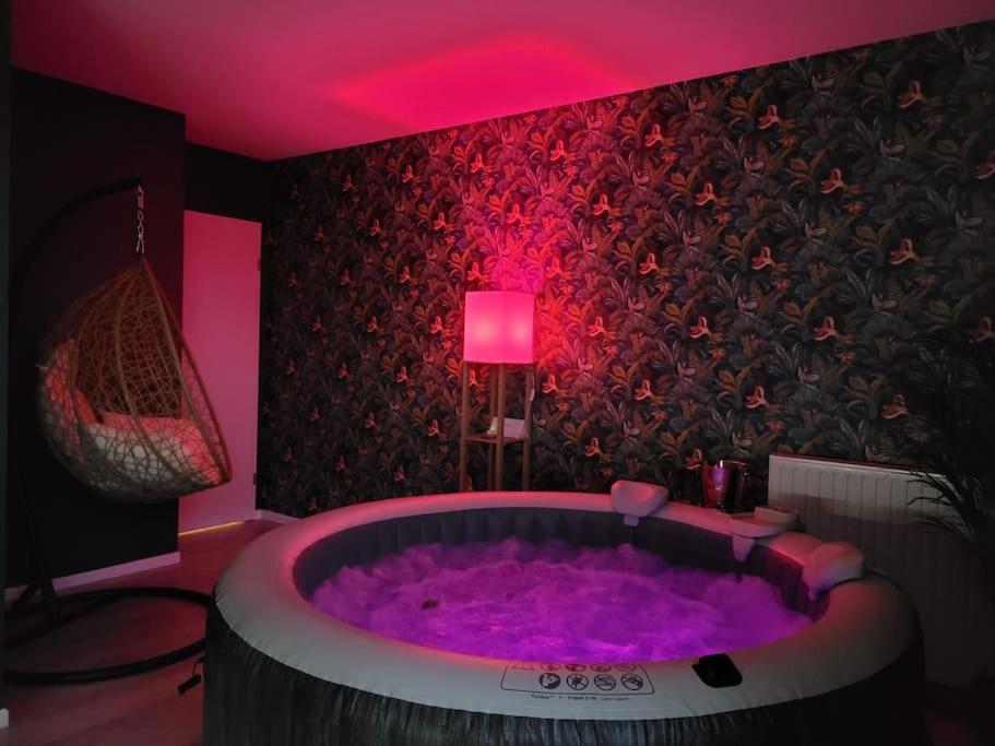 une grande baignoire violette dans une pièce avec un éclairage rose dans l'établissement Amour & Romance l Jacuzzi XXL l Table de massage, à Vigneux-sur-Seine