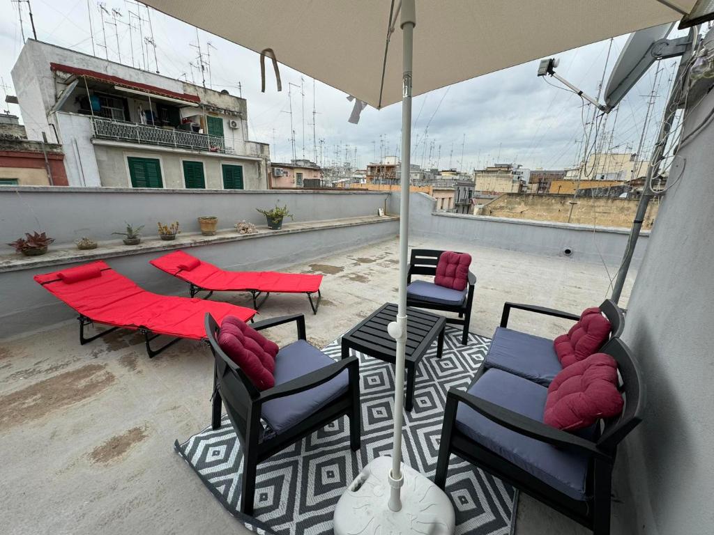une terrasse avec des chaises, des tables et un parasol dans l'établissement PrincipeAmedeo apartment 89 steps to the terrace, à Bari