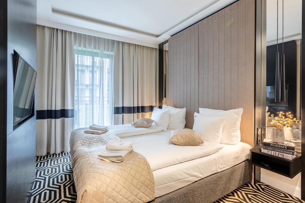 a bedroom with a large white bed with a window at Ambria Apartments Promenada in Świnoujście