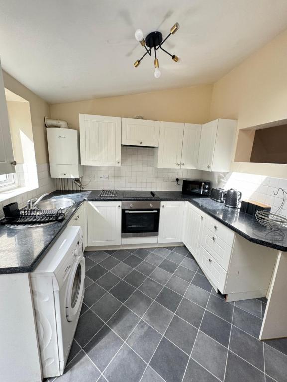 a kitchen with white cabinets and a washer and dryer at Shine Lodge in Kent
