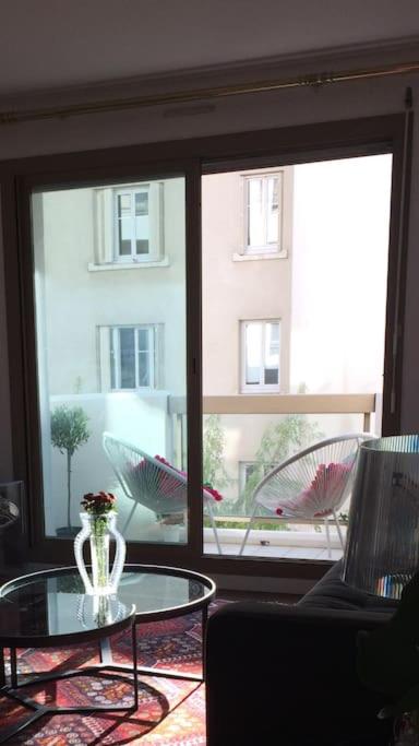 Cette chambre dispose d'une table en verre et d'une grande fenêtre. dans l'établissement Appartement cosy et calme - au cœur de Levallois - avec balcon, à Levallois-Perret