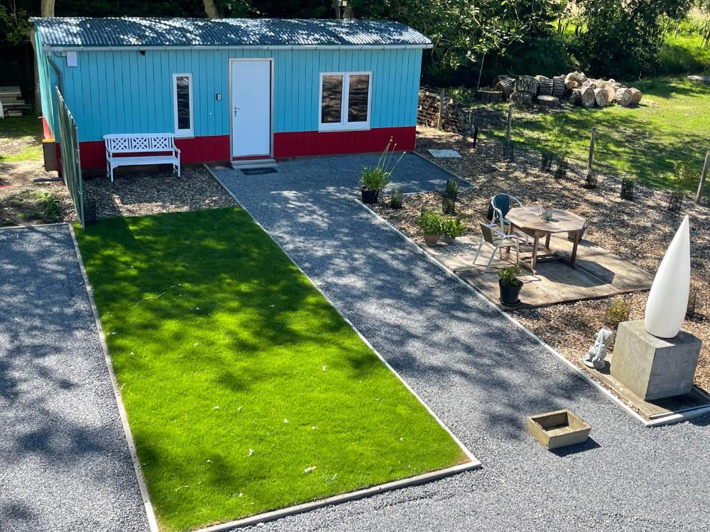 un giardino con una piccola capanna con panchina ed erba di Uniek Tiny house nabij de kust in mooie polders a Zuienkerke