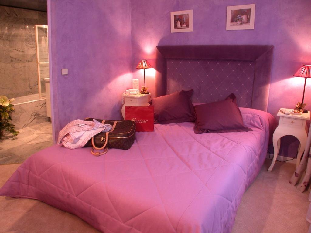 a bedroom with a pink bedspread and pink pillows at Hotel Le Festival in Cannes