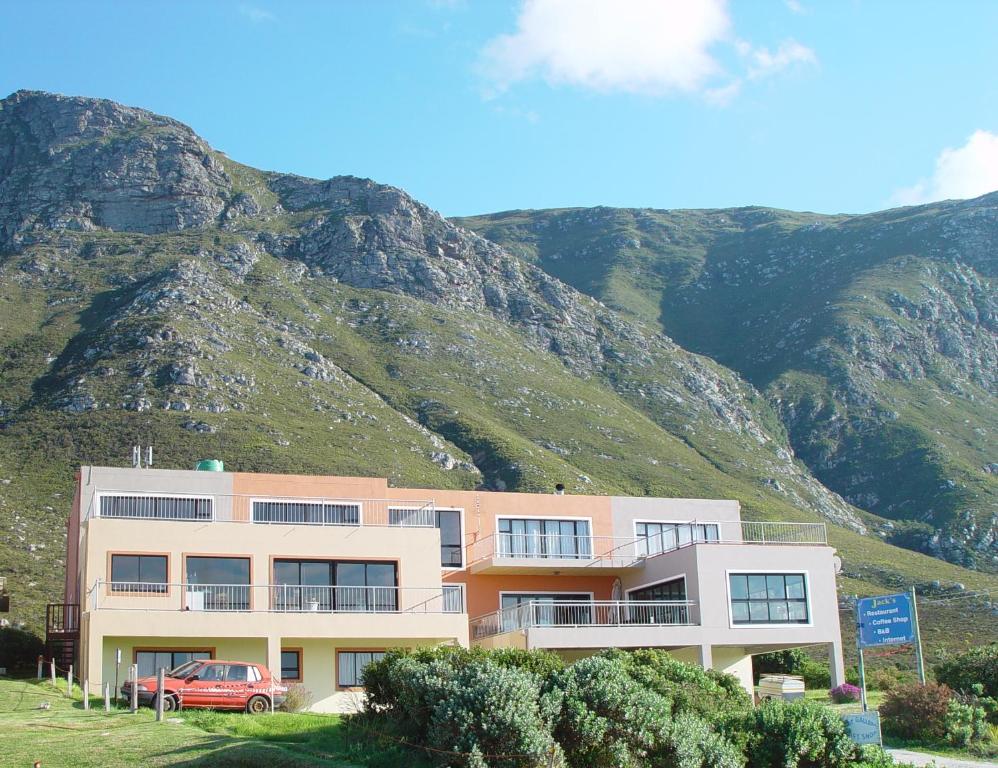 a building with a mountain in the background at Jack's Seaview Inn in Bettyʼs Bay