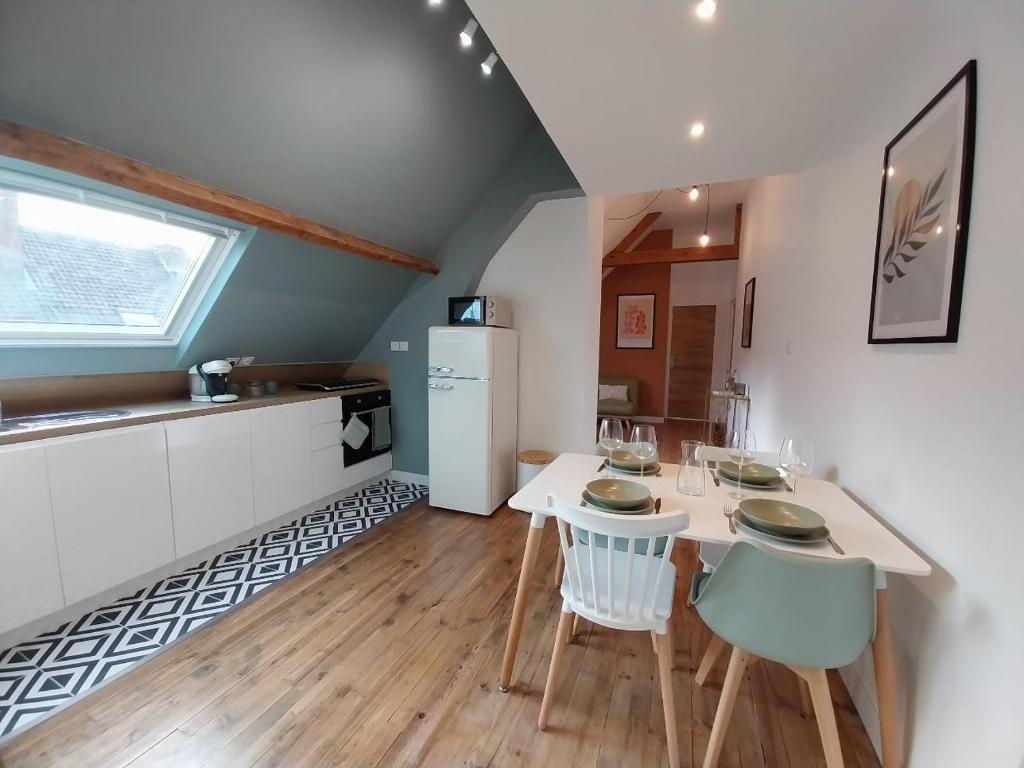 une cuisine et une salle à manger avec une table et des chaises blanches dans l'établissement Au 26 Calais T3, à Calais