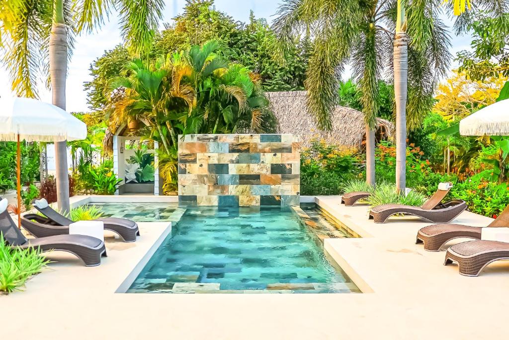 a pool in the middle of a yard with chairs and a swimming pool at Les Voiles Blanches - Luxury Lodge in Tamarindo