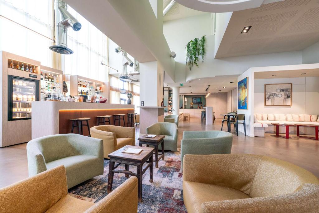 a lobby with chairs and tables and a bar at Best Western Premier Le Masq H&ocirc;tel in La Rochelle