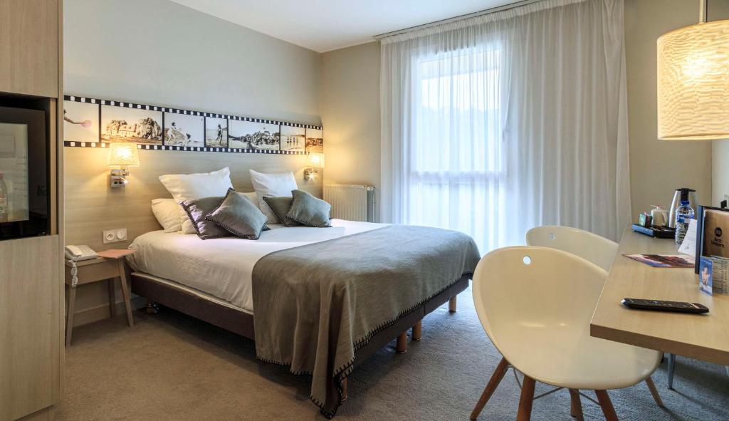 a hotel room with a bed and a desk and a table at Best Western Les Bains Hotel et SPA in Perros-Guirec