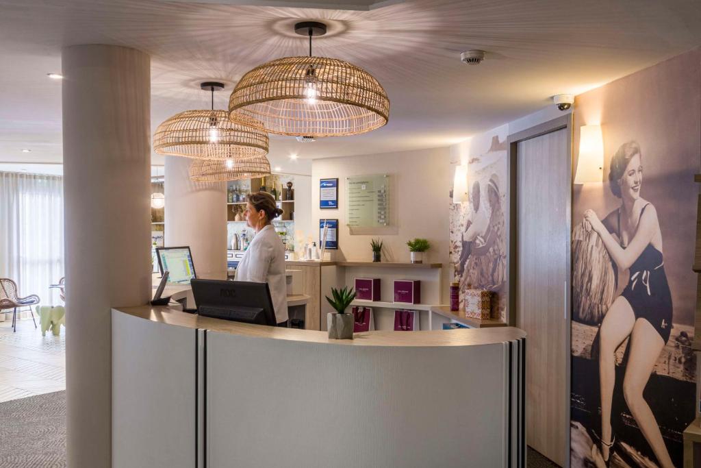 a woman standing at a counter in a salon at Best Western Les Bains Hotel et SPA in Perros-Guirec