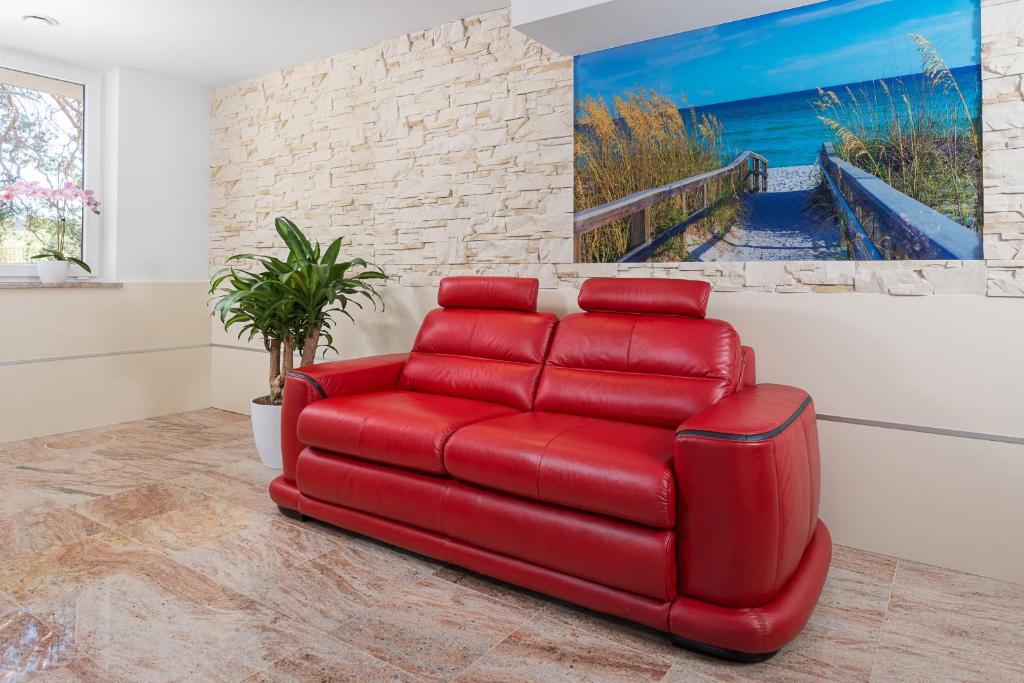 ein rotes Ledersofa im Wohnzimmer mit einem Gemälde in der Unterkunft Apartamenty Czarny Kormoran in Hel
