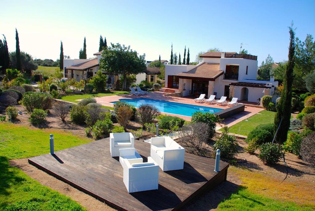 een huis met een zwembad en twee witte stoelen bij 3 bedroom Villa Limni with private pool and gardens, Aphrodite Hills Resort in Kouklia