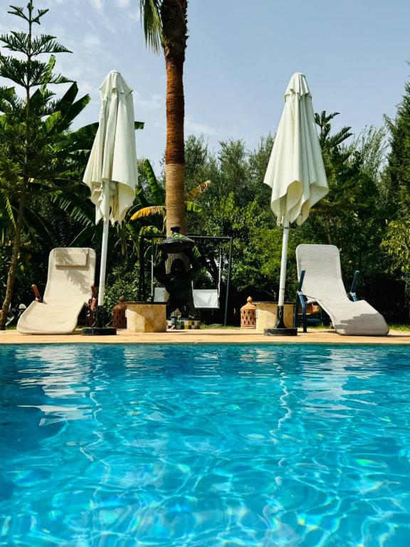 a swimming pool with two white umbrellas and a pool at Villa avec Piscine Chauffée Privée pour Familles in Marrakesh