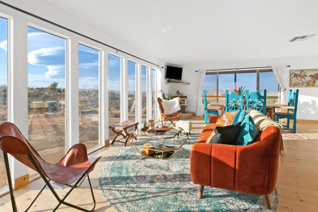 a living room with a couch and chairs and windows at High View Haven - Hot Tub, Fire Pit, BBQ in Joshua Tree! home in Joshua Tree