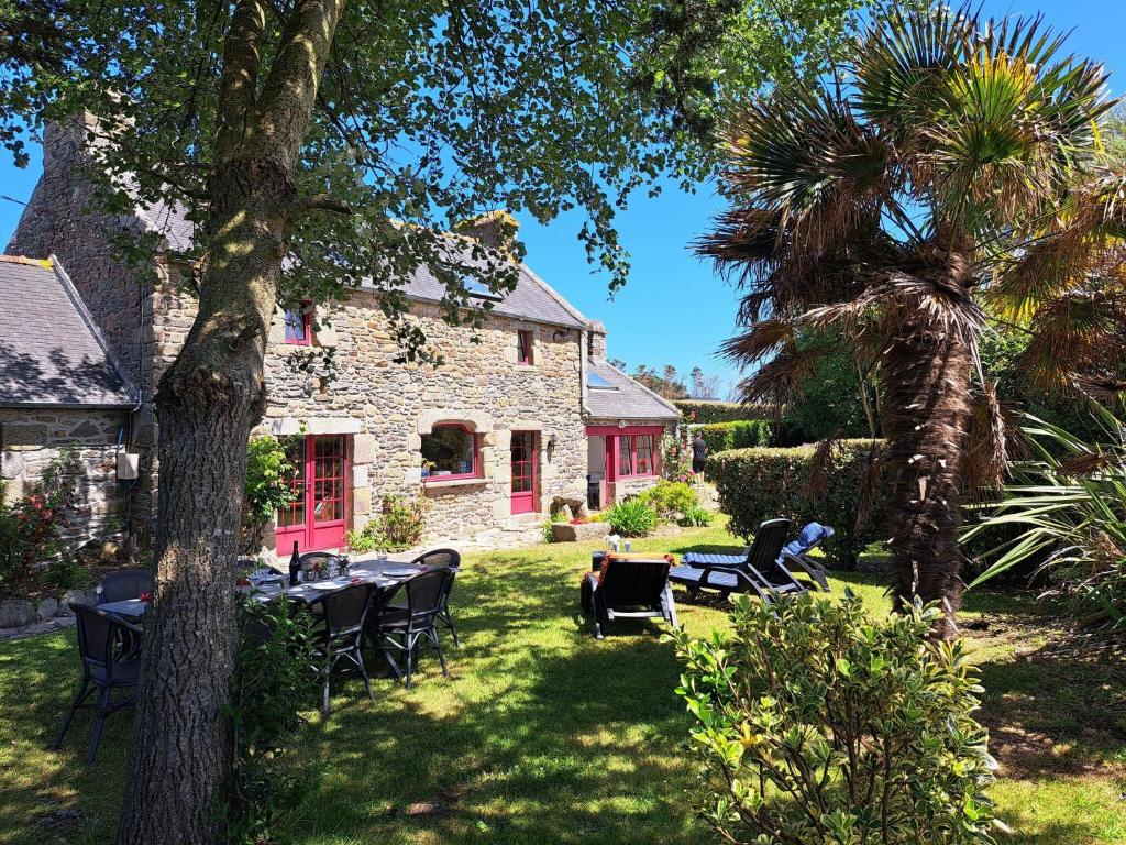 un jardin avec des tables et des chaises en face d'une maison dans l'établissement Stone House in Portsall near Treompan Beach, à Ploudalmézeau