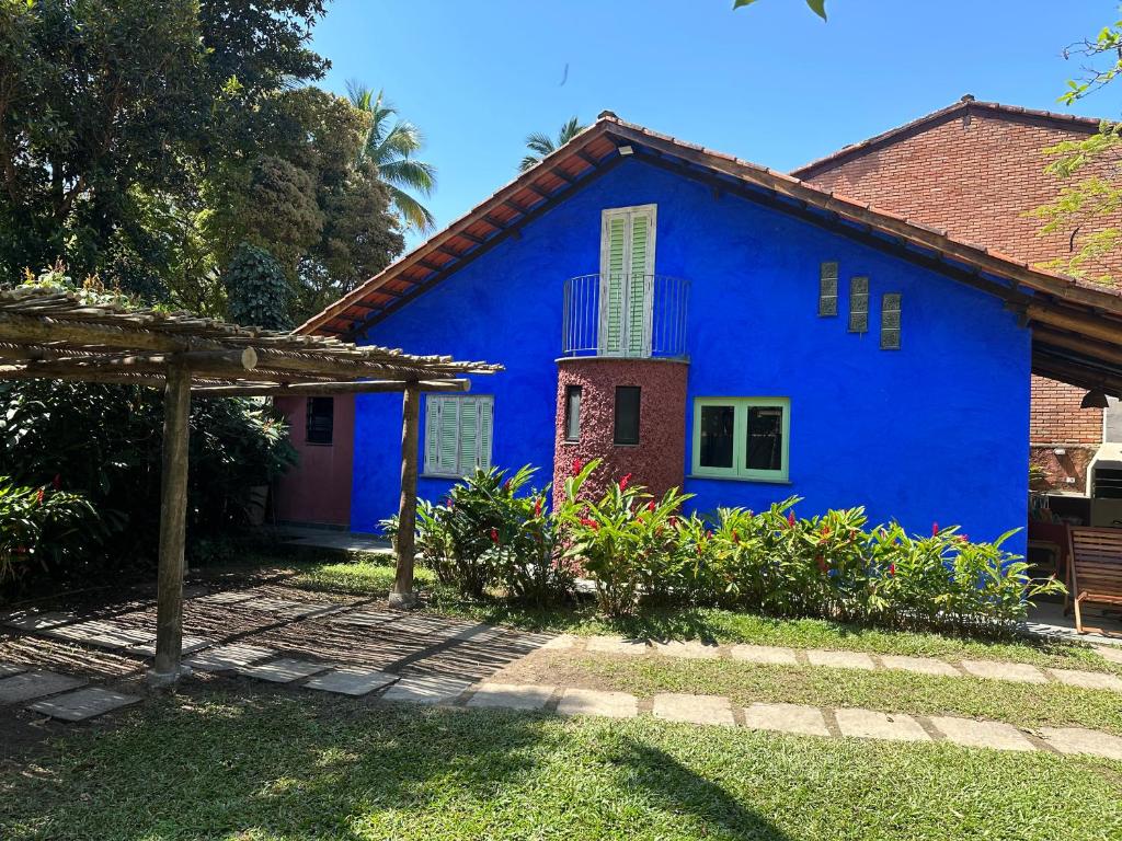 ein blaues Haus mit einer roten Tür im Hof in der Unterkunft Vila dos Tangarás, Casa 1 Praia, a 30m do mar in Toque Toque Grande