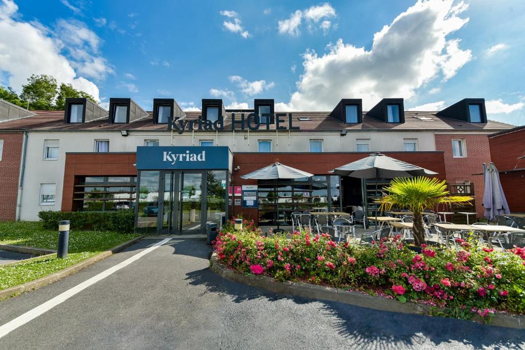 a hotel with tables and chairs in front of a building at Kyriad Crepy En Valois in Crépy-en-Valois