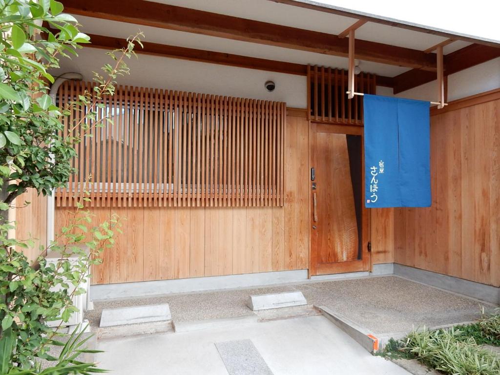 una puerta delantera de una casa con un cartel azul en ella en Yadoya Sanbou en Kioto