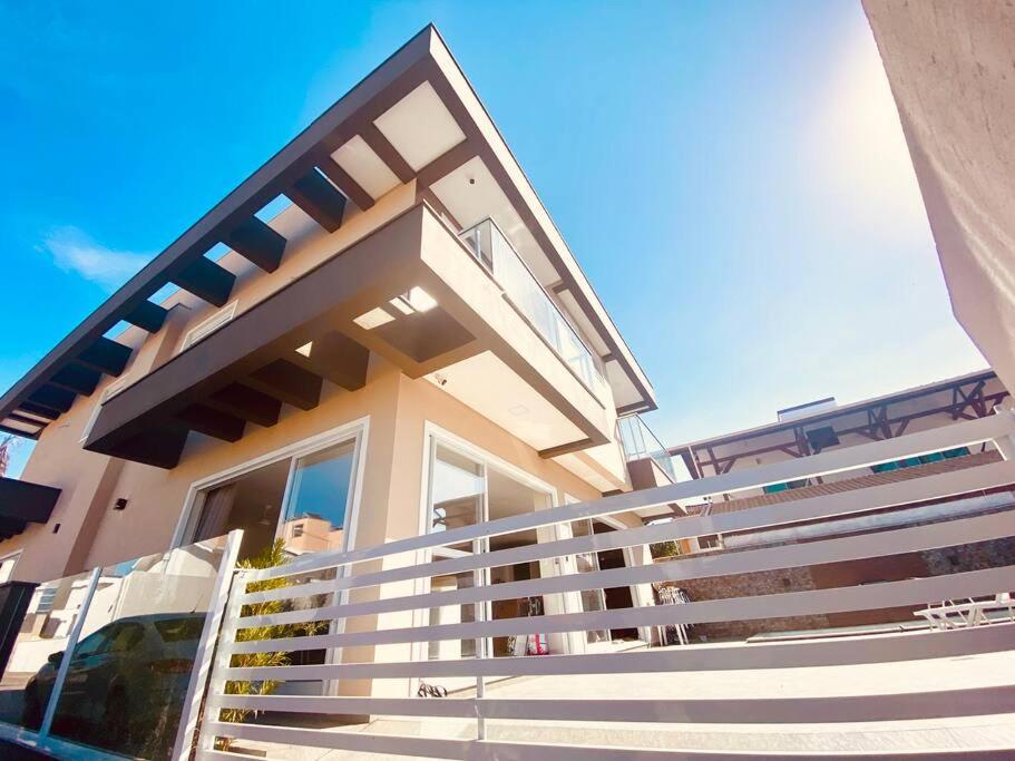 une maison avec une balustrade blanche devant elle dans l'établissement Casa 3 Condomínio Pé na Areia Ponta do Papagaio, à Palhoça