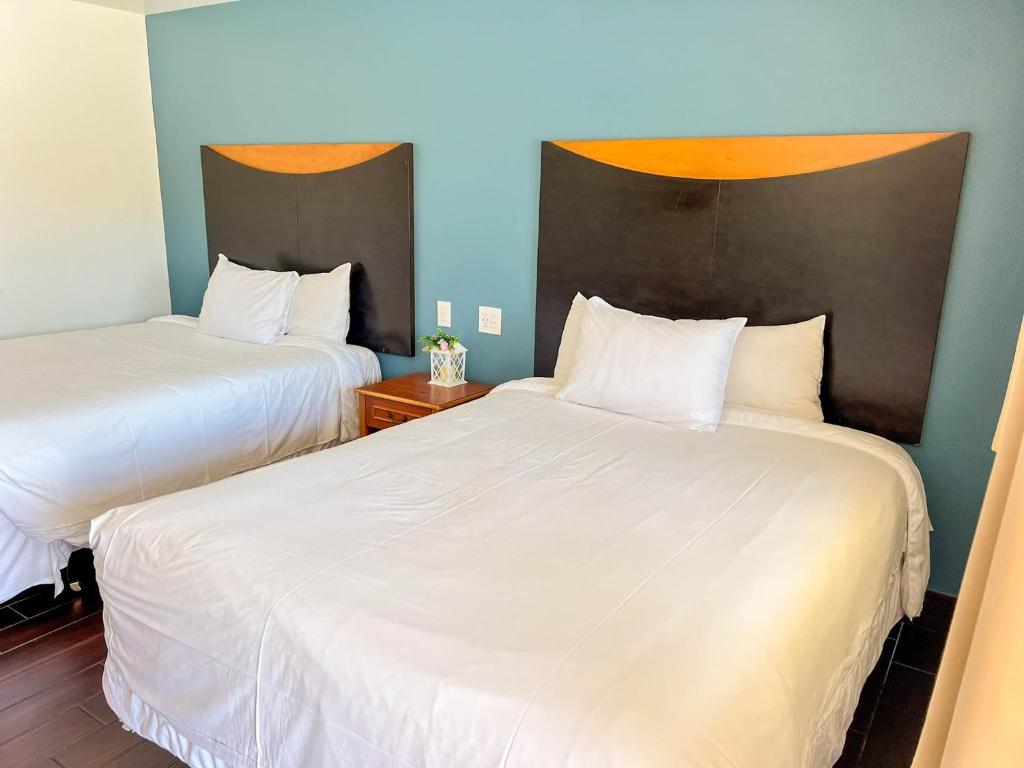 zwei Betten in einem Hotelzimmer mit weißen Laken in der Unterkunft Town and Country Inn in Santa Barbara