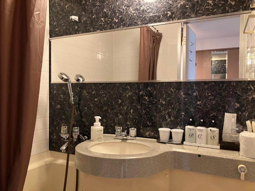 a bathroom with a sink and a mirror at HOTEL LiVEMAX BUDGET Amagasaki in Amagasaki