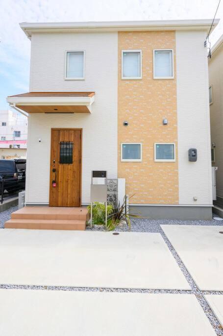 a white house with a brown door on it at Paradiso北谷 in Okinawa City