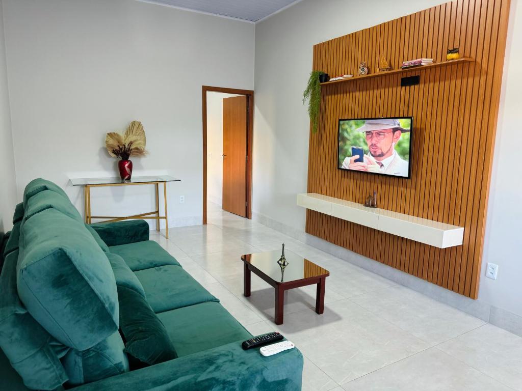 a living room with a green couch and a tv at Casa Em Goiânia - Bairro Capuava in Goiânia