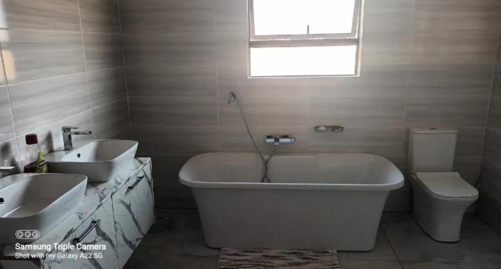 a bathroom with a sink and a tub and a toilet at Nature Home Near Sun City in Maile