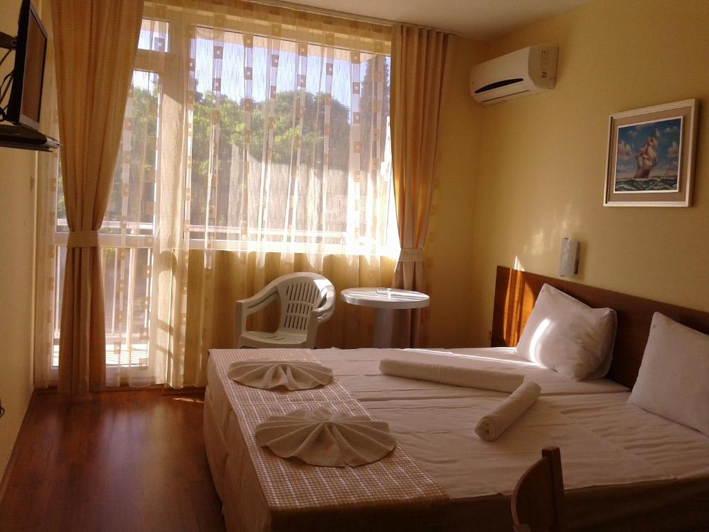 1 dormitorio con 1 cama y ventana con silla en Stephanovy Guest House, en Sozopol