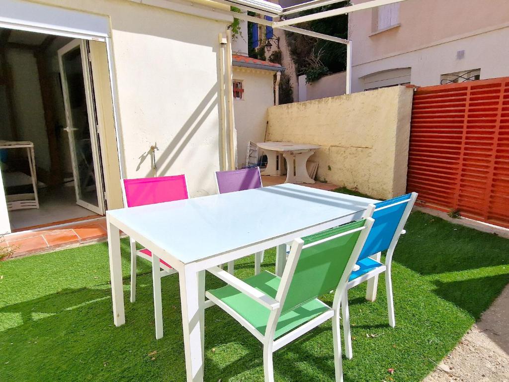 une table et des chaises blanches sur une pelouse dans l'établissement Maison à Banyuls: Wifi, jardin, climatisation, à 5 min de la plage, proche centre et commerces - FR-1-309-472, à Banyuls-sur-Mer