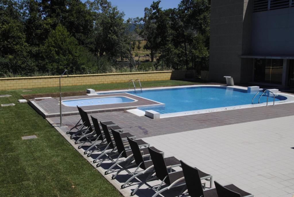 una piscina con sillas en un patio en El Salugral Termal Resort, en Hervás