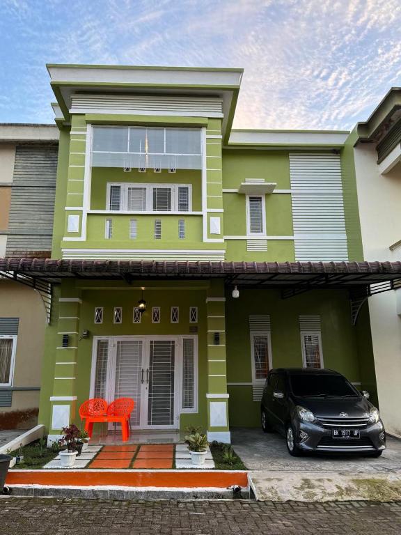 a green house with a car parked in front of it at Villa Dream HillPark Sibolangit BerastagiView in Bandarbaru