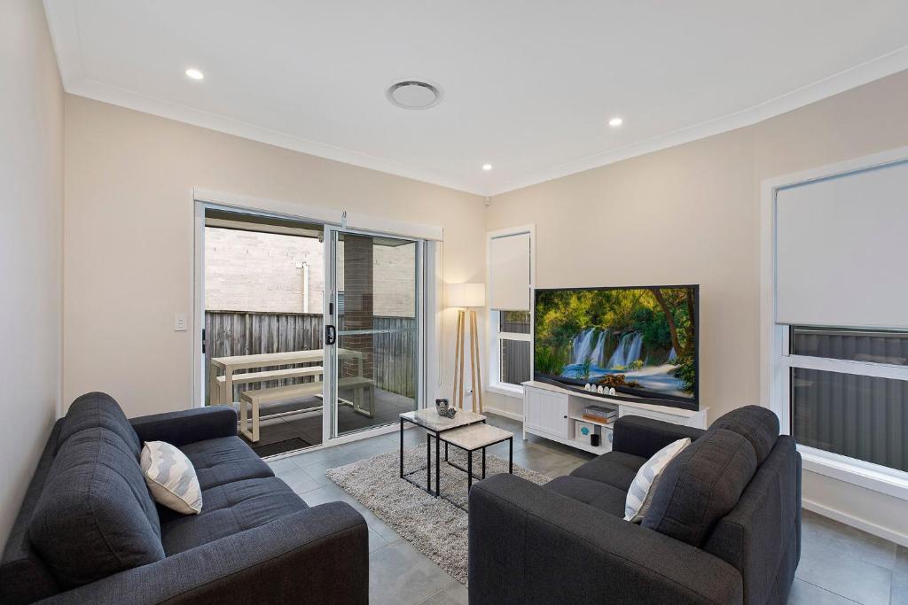 a living room with two couches and a flat screen tv at Sandy Feet Retreat in The Entrance