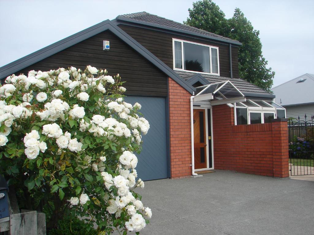 una casa con un garaje azul con un montón de rosas blancas en Aroha Riccarton Bed and Breakfast, en Christchurch