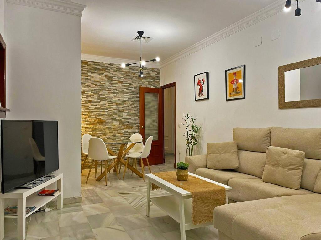 salon z kanapą, telewizorem i stołem w obiekcie Apartamento Armas - Ole Solutions w mieście Jerez de la Frontera