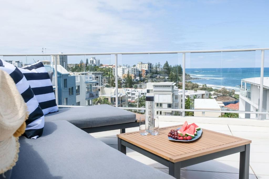 a balcony with a couch and a table with a bowl of fruit at Hamptons Style Penthouse at Kings Beach in Caloundra