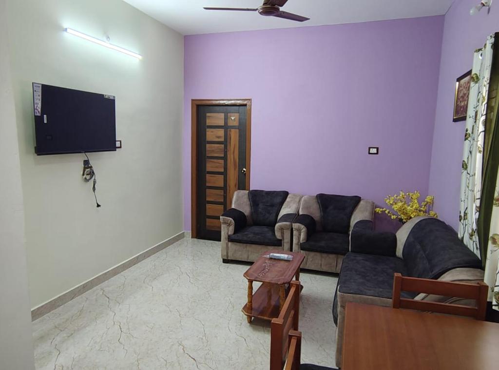 Una sala de estar con un sofá y un televisor de pantalla plana. en LP Homestay, en Yelagiri