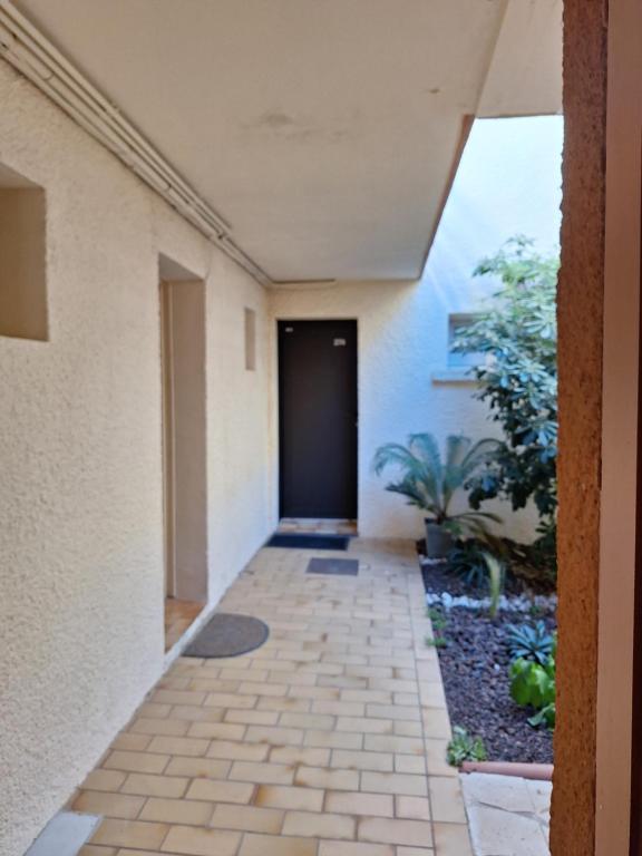 un pasillo de un edificio con una puerta negra en Mimilou Eleuthera 300 m centre naturiste, en Cap d'Agde